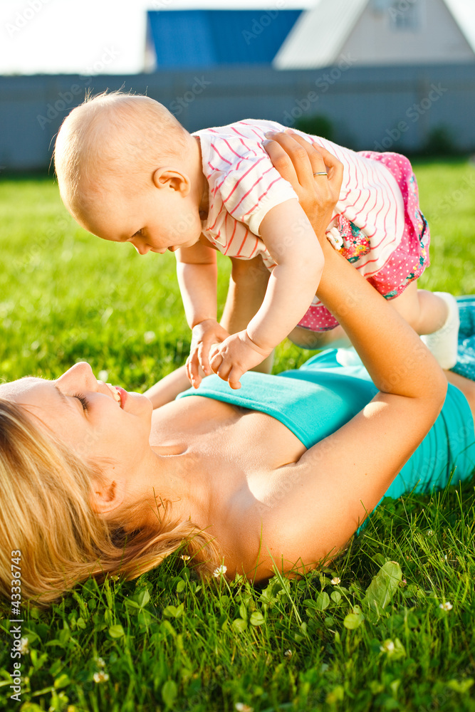 mother lying on the grass and holding baby