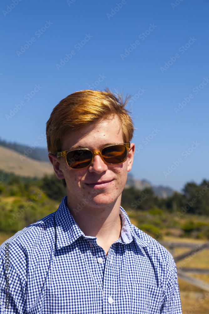 cool teenage boy with sunglasses walks happy on the meadow