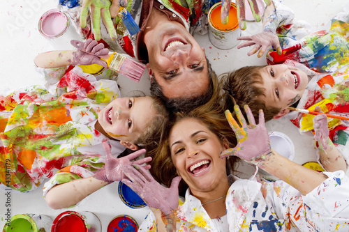 Hispanic family covered in paint laying on floor photo