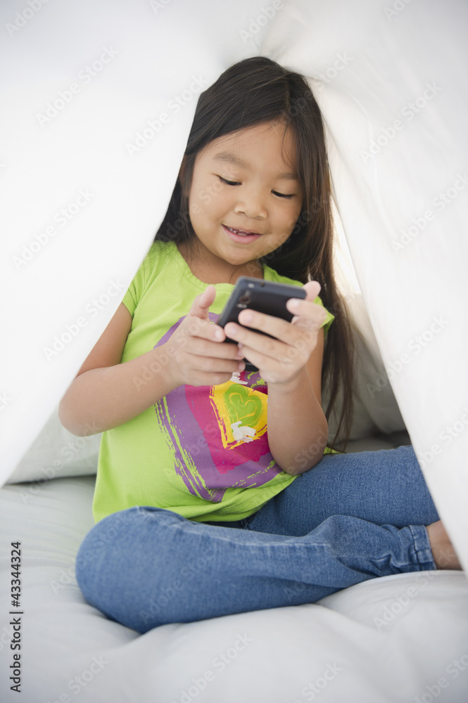 Korean girl using cell phone under sheet Korean girl using cell phone under sheet