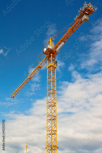 Tall white tower crane against bright blue sky.