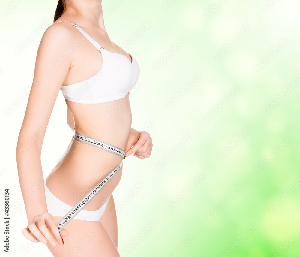 girl taking measurements of her body, green blurred background.