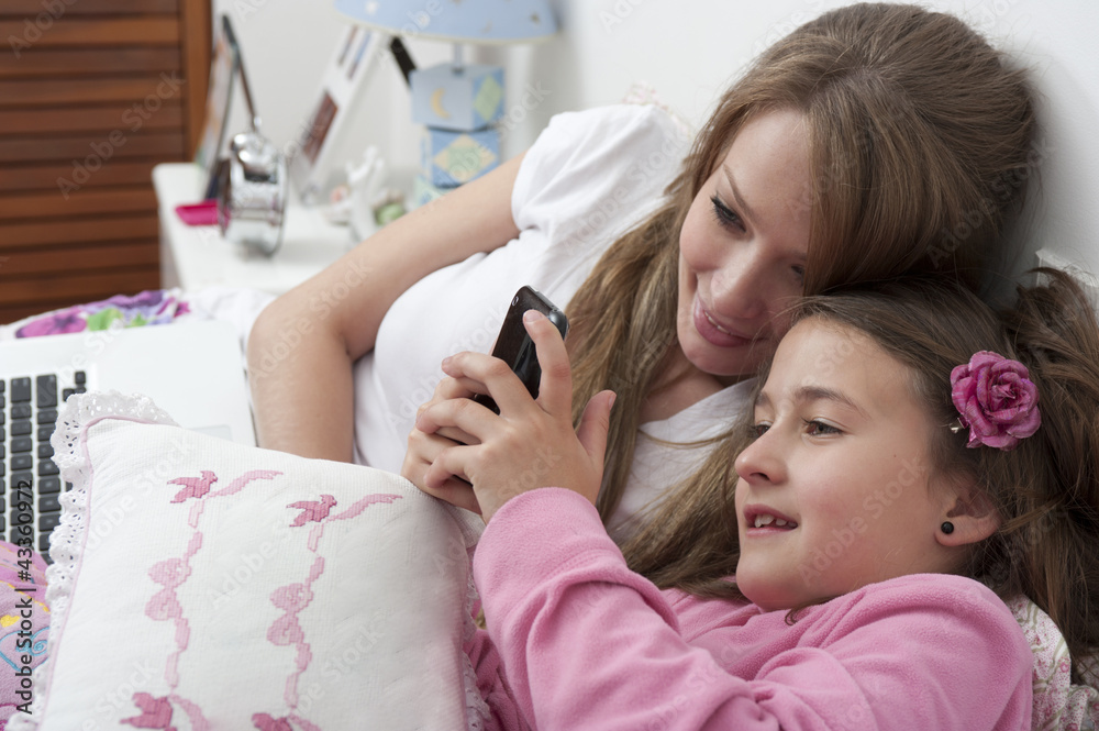 © GM Visuals/Blend Images - Hispanic mother and daughter looking at cell phone