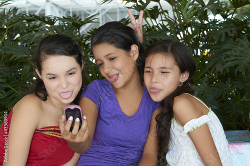Hispanic girls taking self-portrait with cell phone