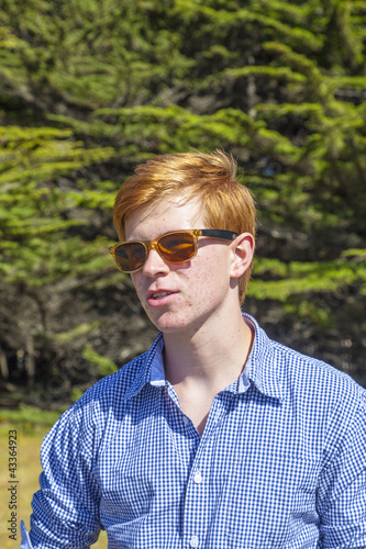 teenage boy with sunglasses walks happy on the meadow © travelview