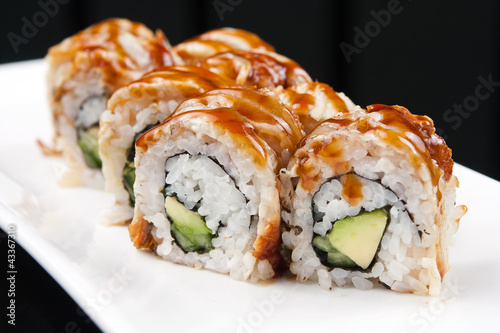 sushi roll on white plate over black background