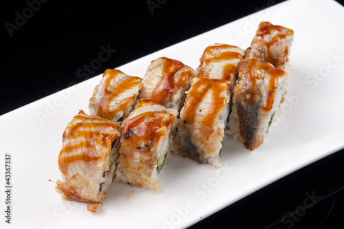 sushi roll on white plate over black background