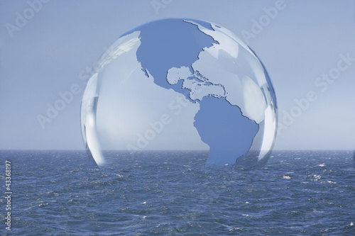 Transparent globe floating on ocean photo