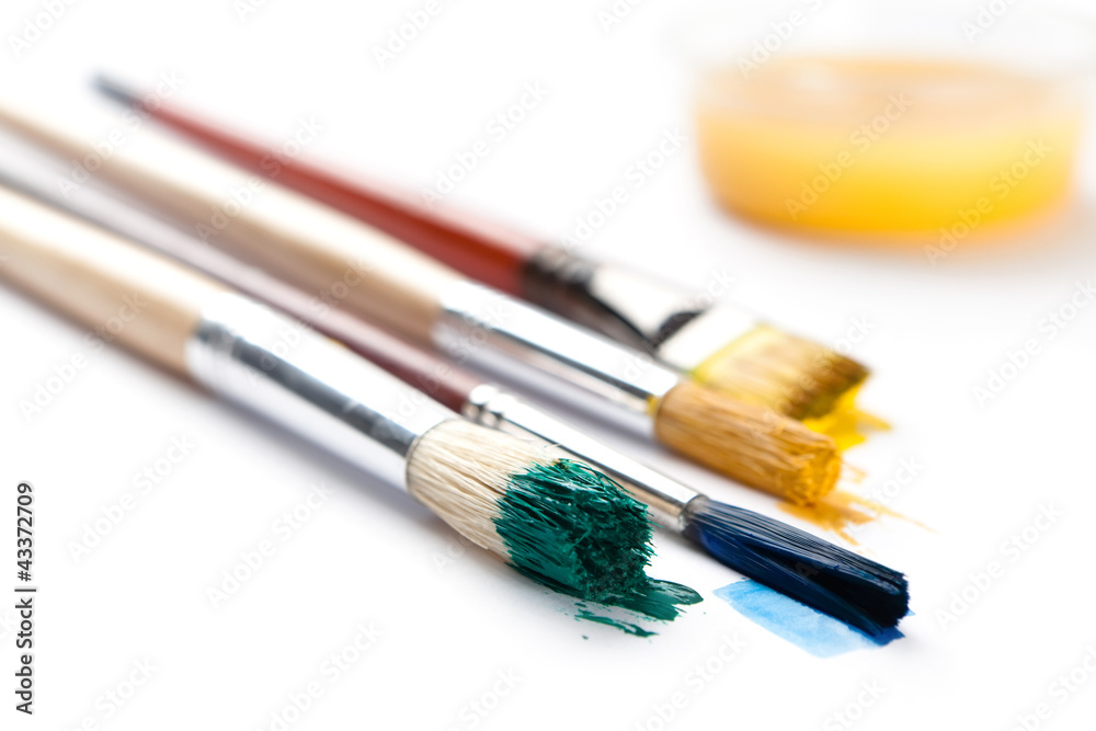 Set of brushes stained with paint near the ink container Set of brushes stained with paint near the ink container
