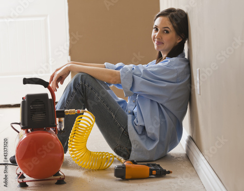 Caucasian woman sitting with compressor and nail gun photo