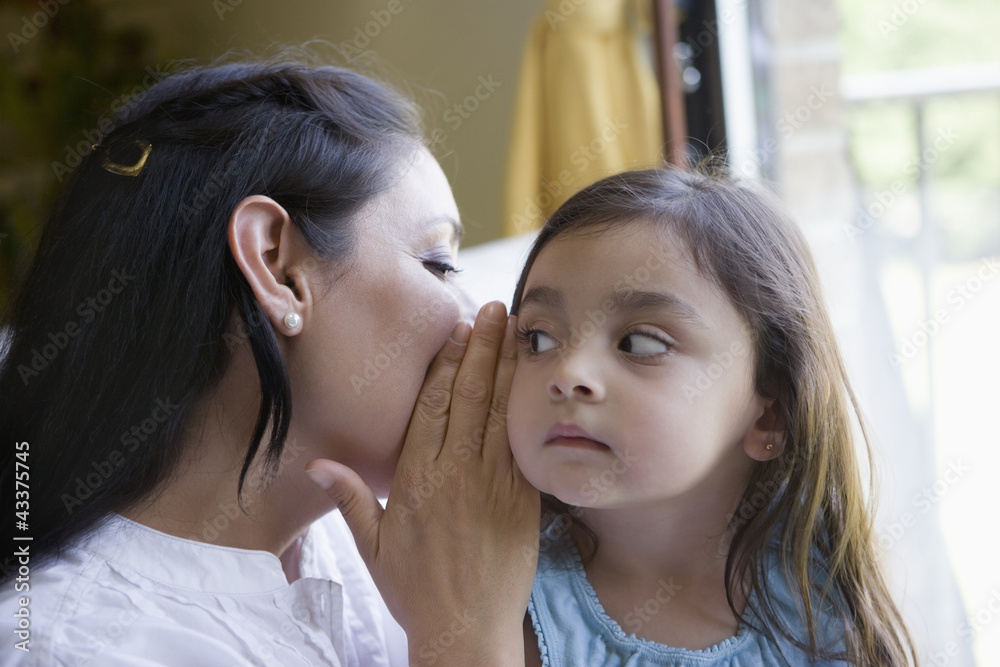 Hispanic mother whispering to daughter Hispanic mother whispering to daughter