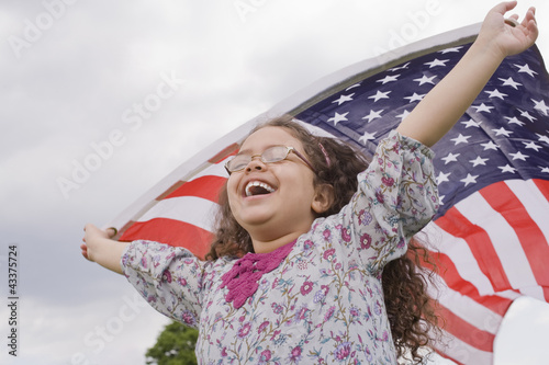 Hispanic girl holding American flag with arms raised photo