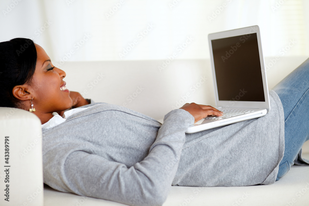 Naklejka premium Young relaxed woman working on laptop