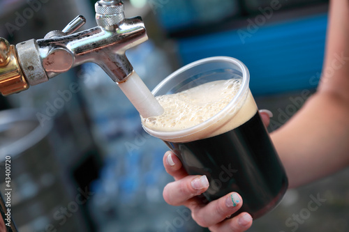 Beer festival pouring dark beer to glass photo