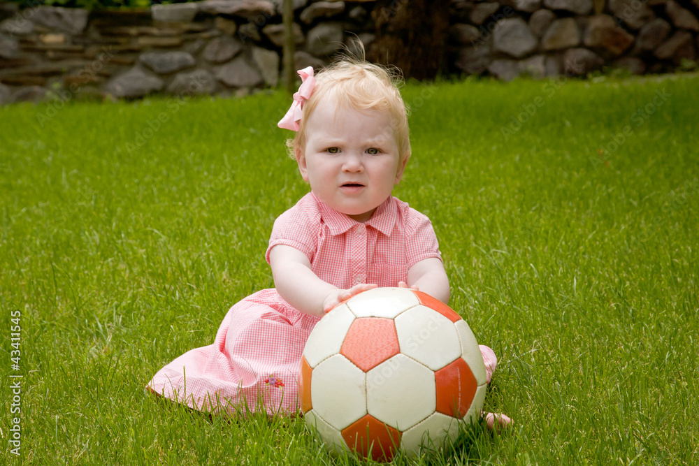 Baby girl sitting on lawn with the ball. Baby girl sitting on lawn with the ball.
