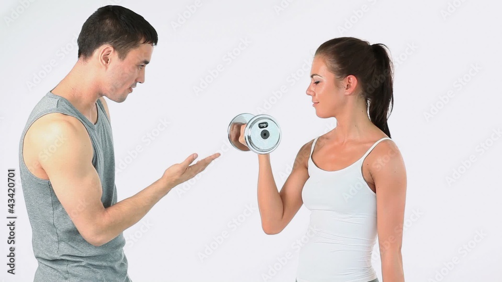 Trainer helping a woman to lift weights Trainer helping a woman to lift weights