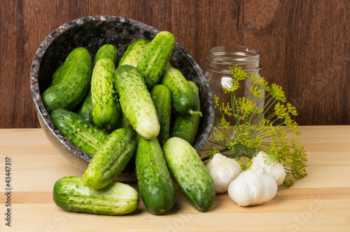 Bowl of pickles with jar and garlic