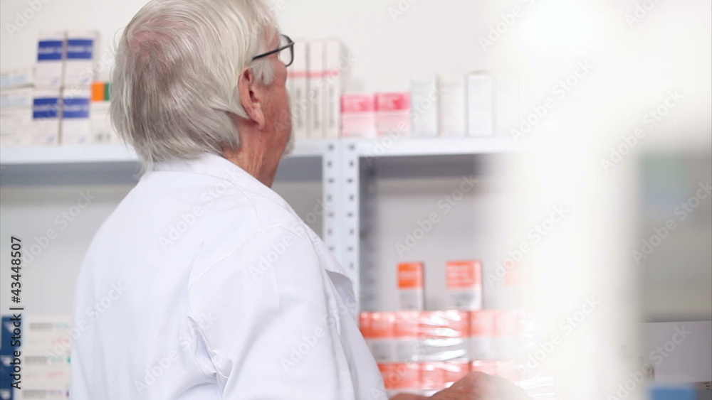 Pharmacist looking at pills in a shelf Pharmacist looking at pills in a shelf