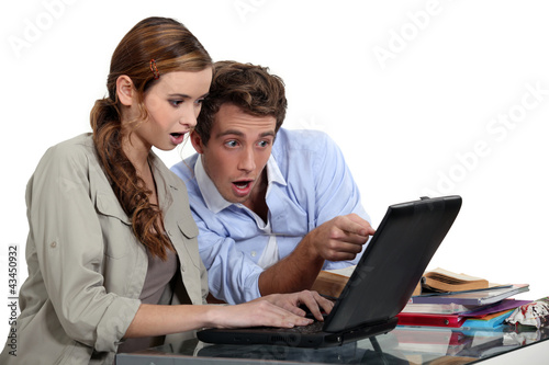 Shocked couple pointing at a laptop