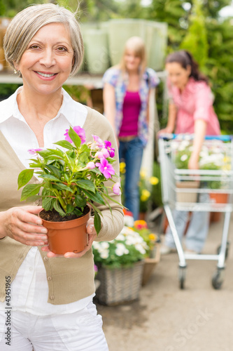 Senior woman hold potted flower garden shop