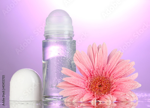 Fototapeta Naklejka Na Ścianę i Meble -  deodorant with flower on purple background
