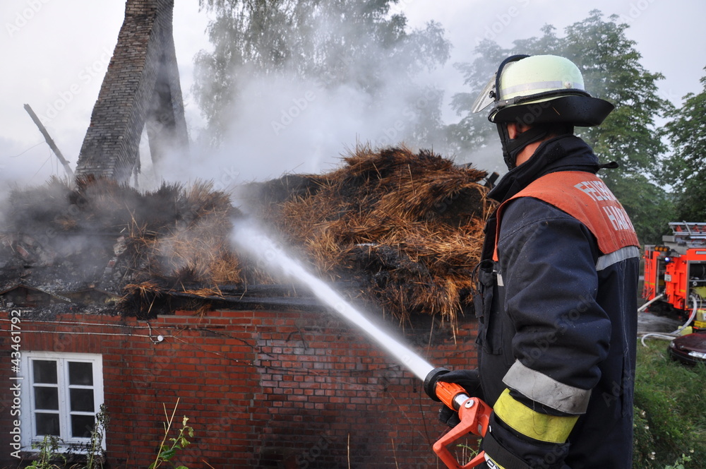 Fototapeta premium Feuerwehrmann löscht Reetdach