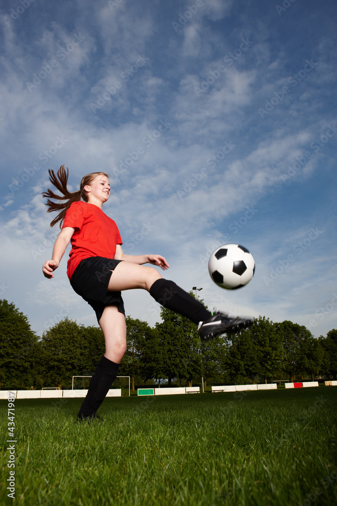 Fototapeta premium Frau beim Fußball hochhalten