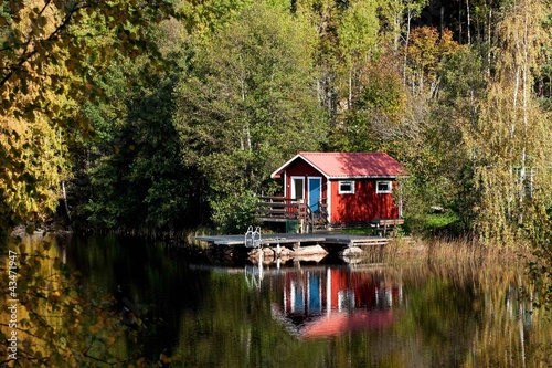Typical Swedish red little cottage at a lake