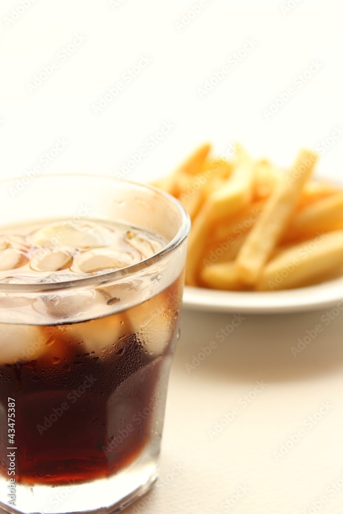 Glass of cola and fried potatoes on plate Glass of cola and fried potatoes on plate