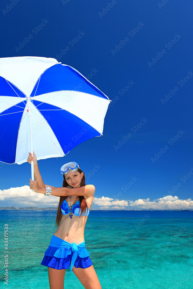 水辺でパラソルを持つ笑顔の女性