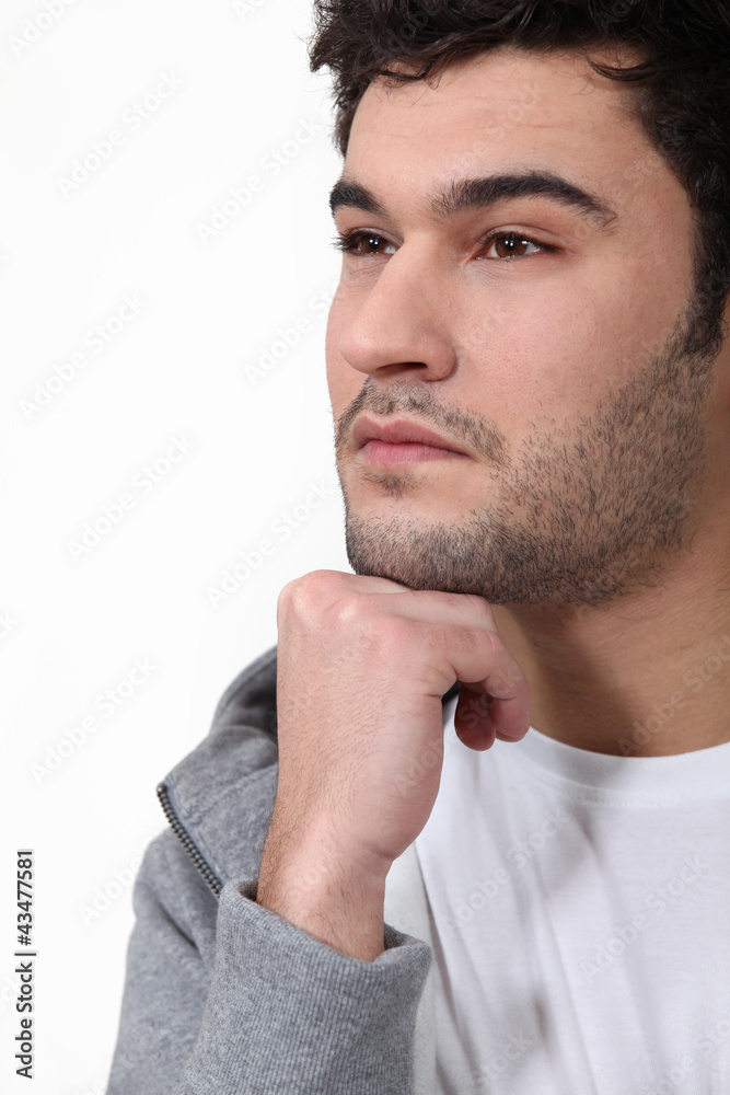 Fototapeta premium Pensive man stood touching chin with fist