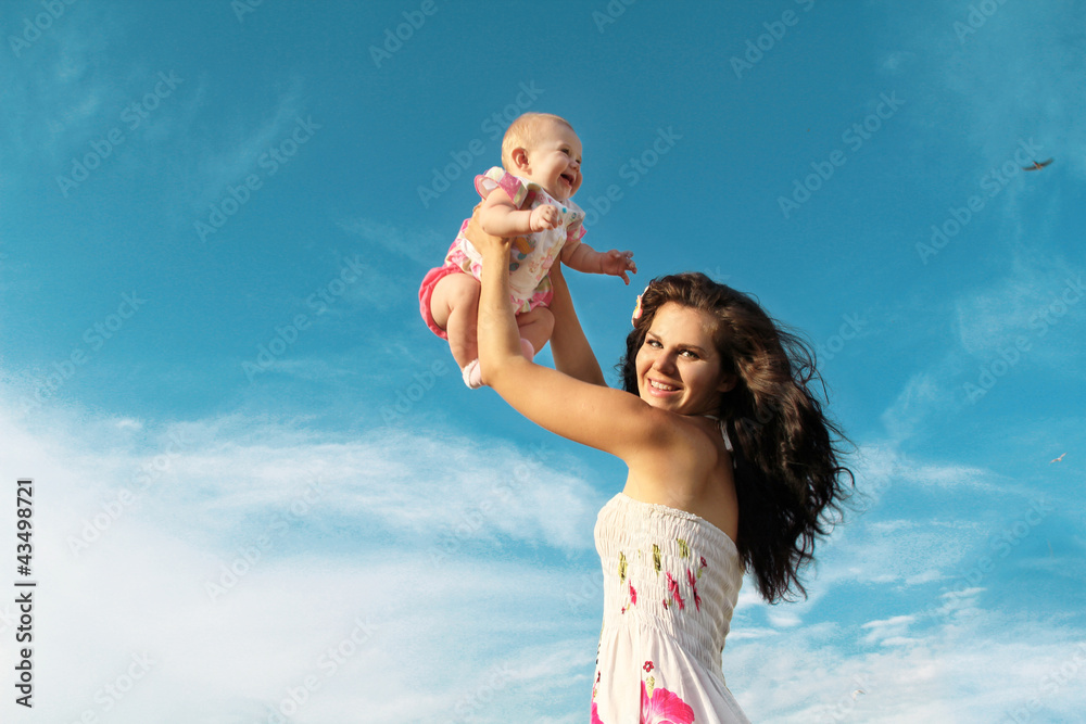 Happy mother playing with baby over blue sky Happy mother playing with baby over blue sky