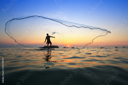 throwing fishing net during sunrise, Thailand
