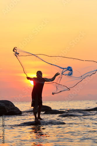 throwing fishing net during sunrise, Thailand