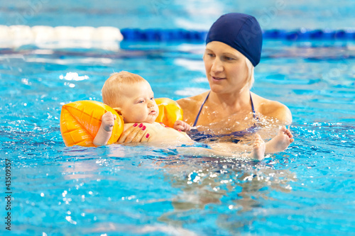 mother teach baby swimming in pool