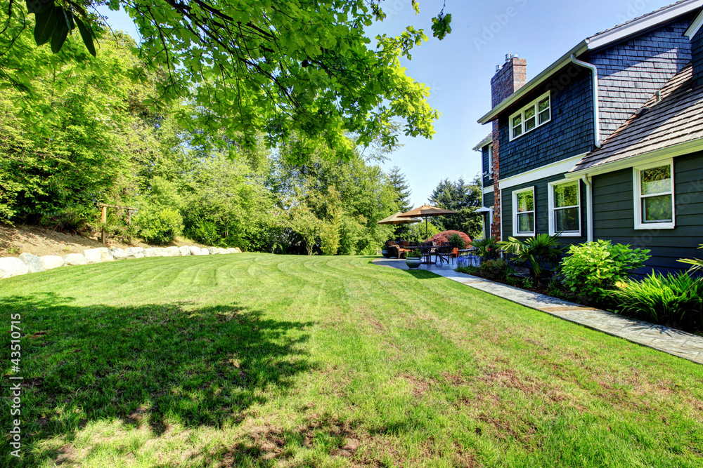 Blue large house with backyard and green landscape. Blue large house with backyard and green landscape.