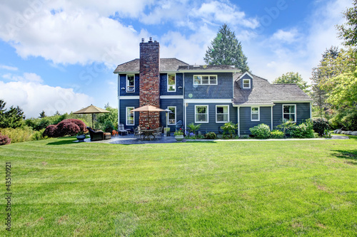 Large blue house with grass and chimney.