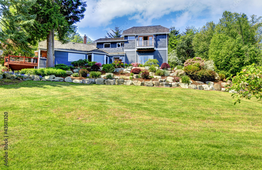 Large blue house with green hill and stone walls. Large blue house with green hill and stone walls.