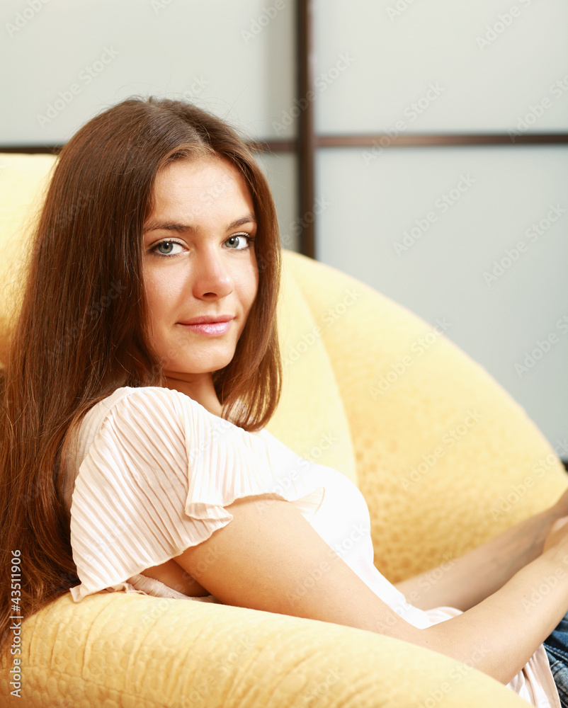 A young smiling woman sitting on the sofa at home