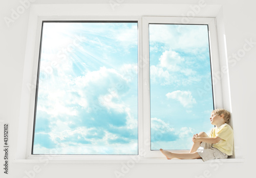 Child sitting on window, enjoying sunshine and dreaming. Big win photo