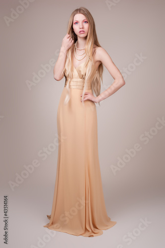Beautiful young woman wearing a sexy beige evening dress