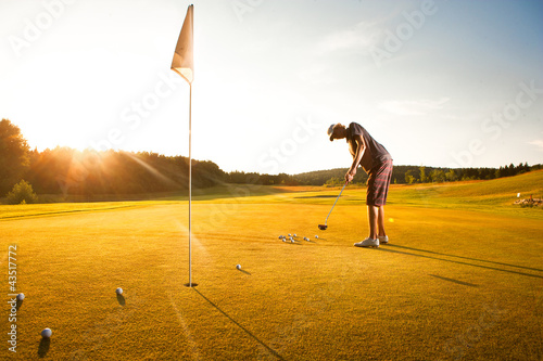 Male golf player practicing a par during sunset