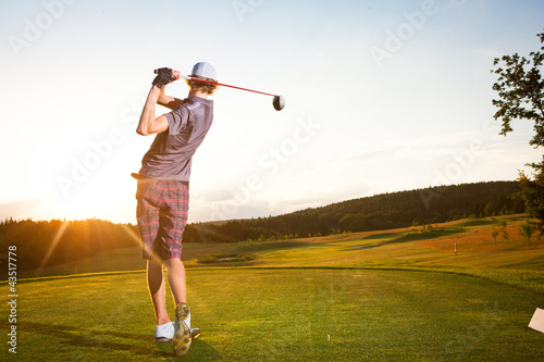 Male golf player teeing off golf ball from tee box