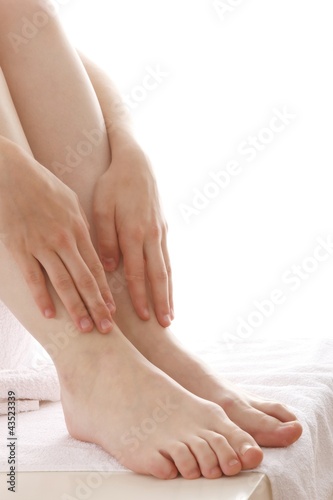 Woman massaging legs (white background) © Knut Wiarda