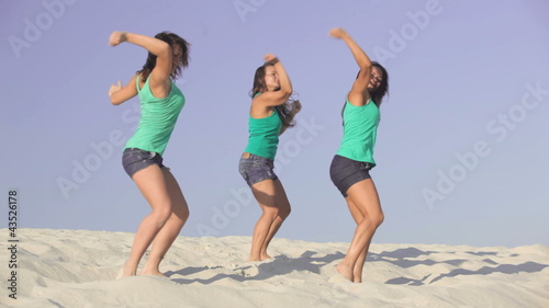 Team of pretty energetic girls dancing on the sand together