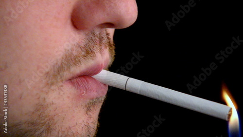 Man lighting a cigarette over black. closeup