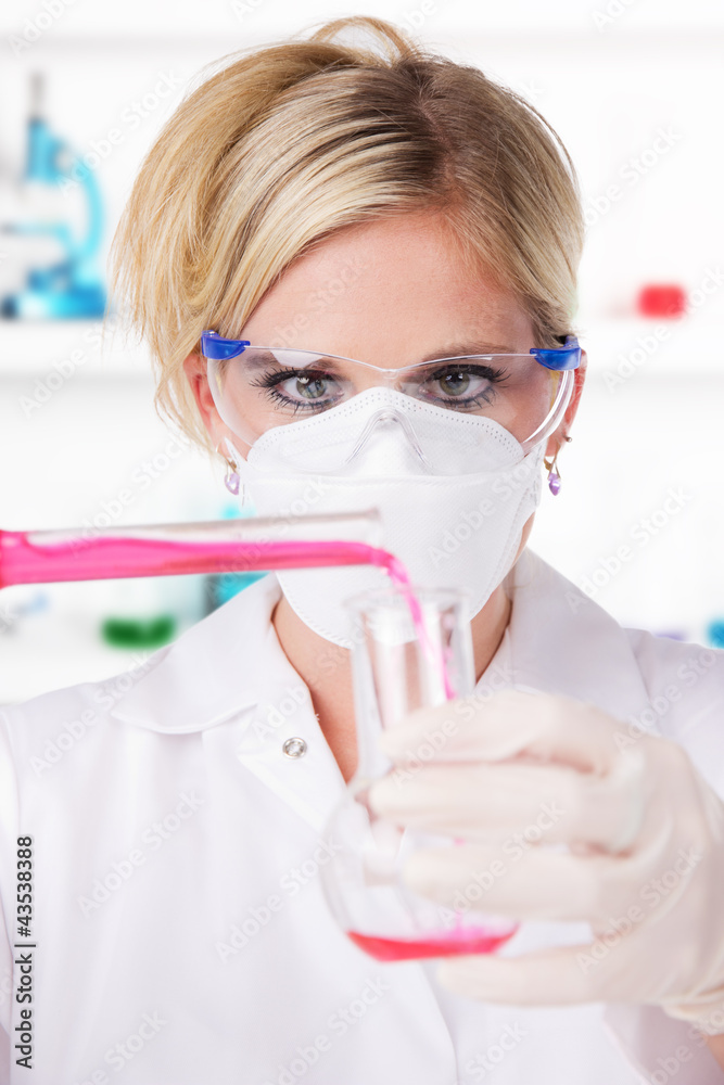 Young attractive laboratory assistant pouring chemical liquid
