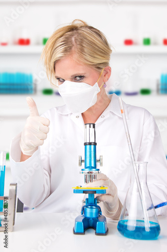 Young attractive laboratory assistant showing thumb up 