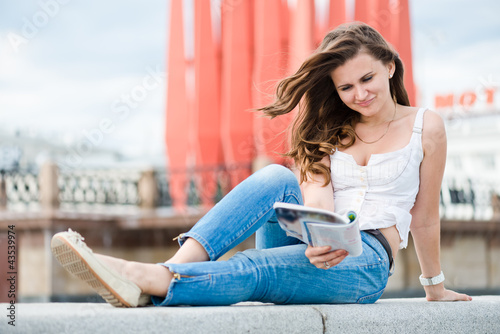 Outdoor portrait of young woman with fashion magazine