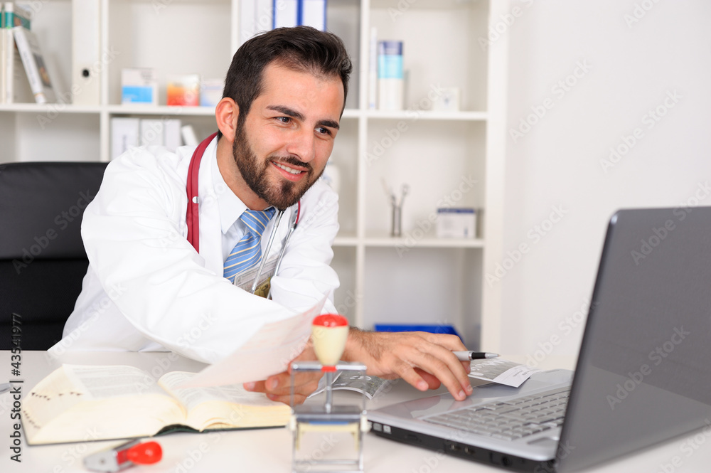 Junger Arzt in der Praxis am Laptop.